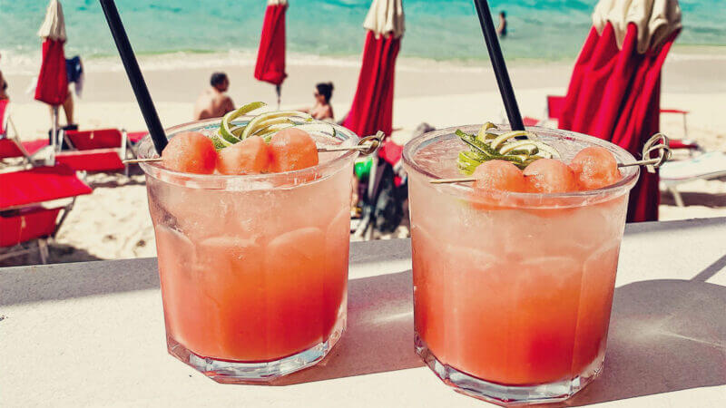Dois drinks na praia de Saint Martin. Acompanhe no texto as 12 comidas típicas de Saint Martin