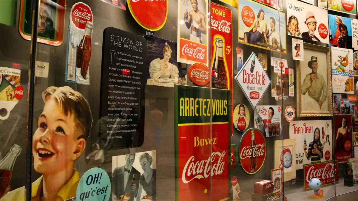 Parede repleta de posters antigos da marca de refrigerante Cola Cola