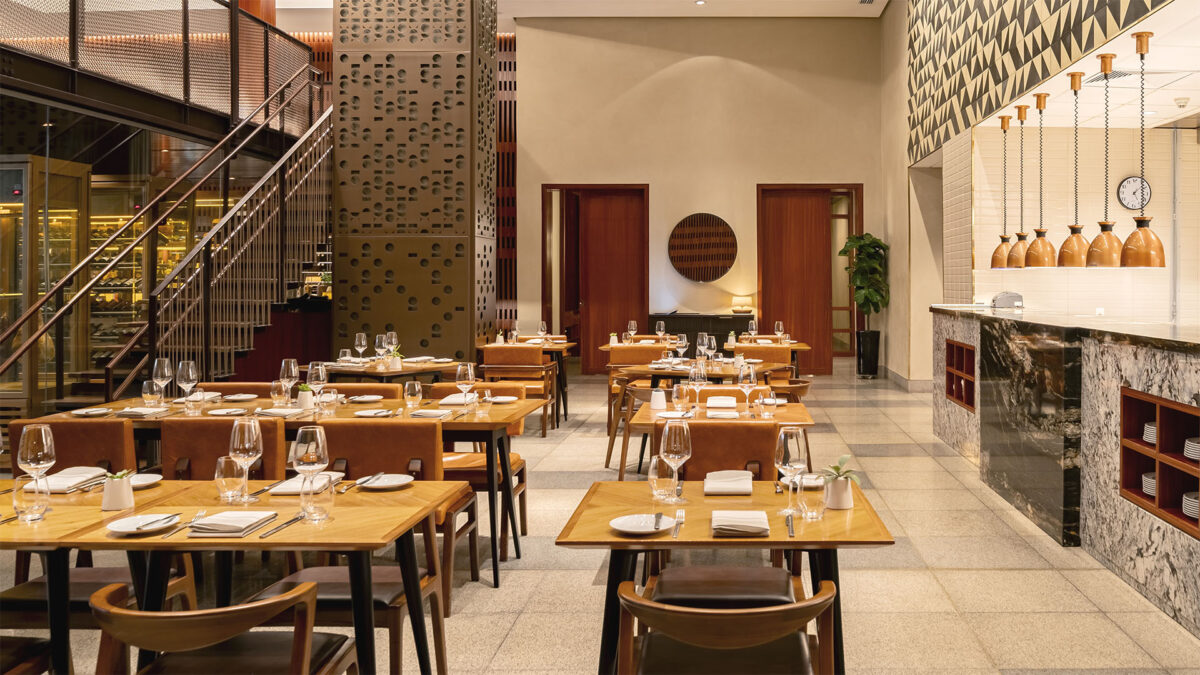 Salão do restaurante do hotel JW Marriott, com as mesas e cadeiras em madeira postas para refeição. Aqui será servido o brunch de natal em 2023