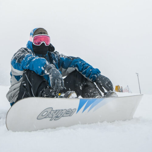 Esquiador sentado na neve sorrindo