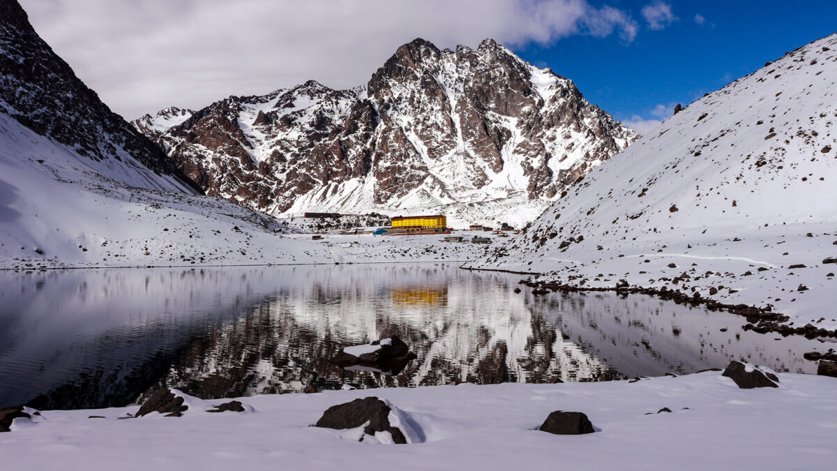 Portillo 2026: guia da estação de esqui mais antiga da América do Sul 4 • Fachada amarela do Hotel Portillo diante da Laguna del Inca congelada